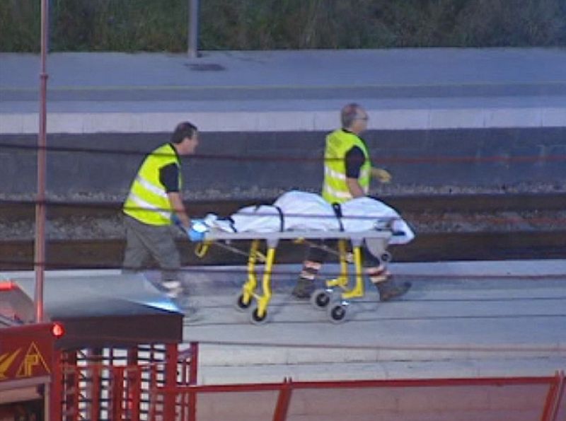 Funcionarios sanitarios trasladan uno de los cuerpos sin vida en la estación de Castelldefels.