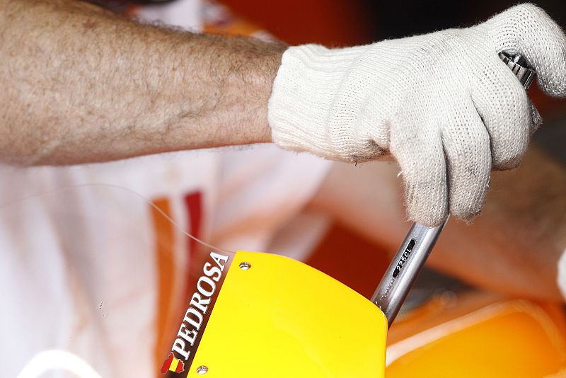 Uno de los mecánicos de Pedrosa trabaja con guantes 'especiales'.