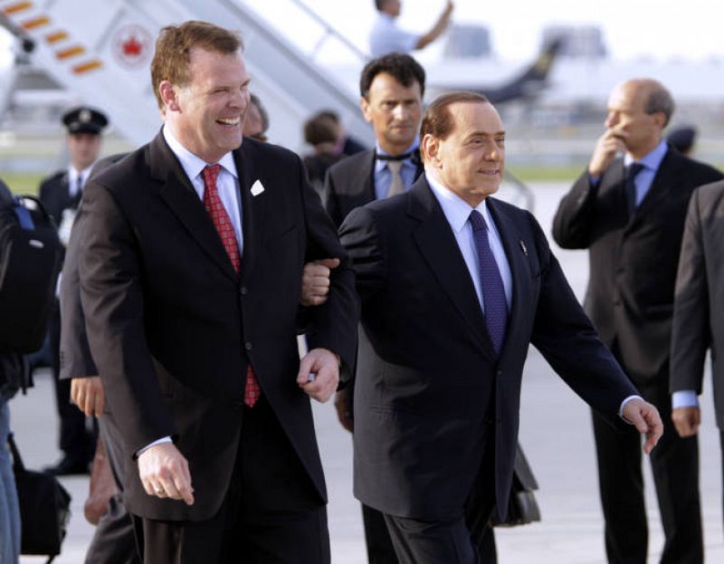 El primer ministro italiano, Silvio Berlusconi, junto al ministro canadiense, John Baird en el aeropuerto canadiense