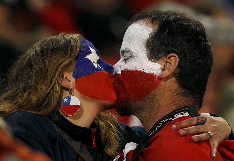 Un pareja de aficionados chilenos besándose mientras esperan a que comience el partido entre Chile y España