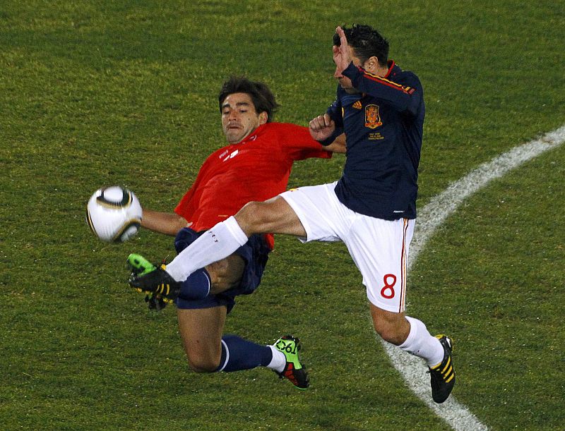 El chileno Estrada pugna por el balón con el jugador español Xavi.