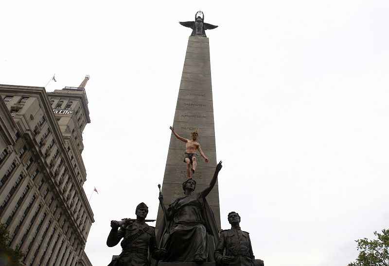 Un manifestante se sube a una estatua para protestar contra la cumbre del G-20 en Toronto