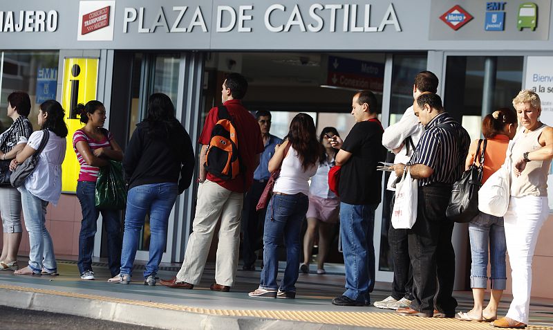 People queue for a bus outside a subway station during morning rush hour in Madrid