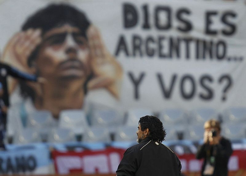 Argentina's coach Maradona stands on pitch in front of banner before the 2010 World Cup quarter-final soccer match between Argentina and Germany