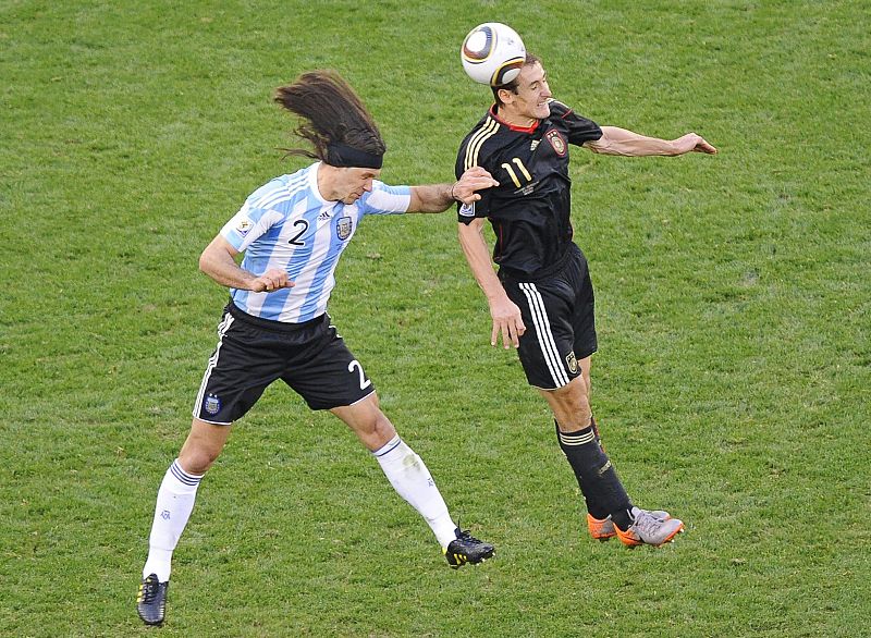 El jugador alemán Miroslav Klose (d) salta por el balón con el argentino Martín Demichelis durante el partido Argentina-Alemania