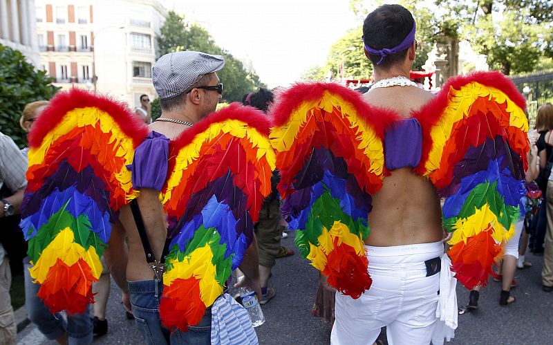 Dos jóvenes con alas que llevan los colores de la bandera del Orgullo Gay