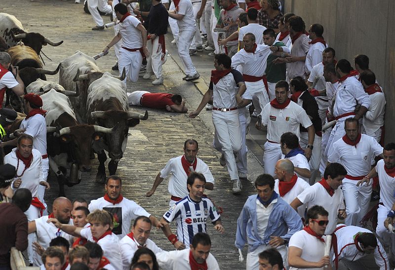 A runner lies on the ground as Penajara fighting bulls charge by on Santo Domingo street during the first running of the bulls on the second day of the San Fermin festival in Pamplona.