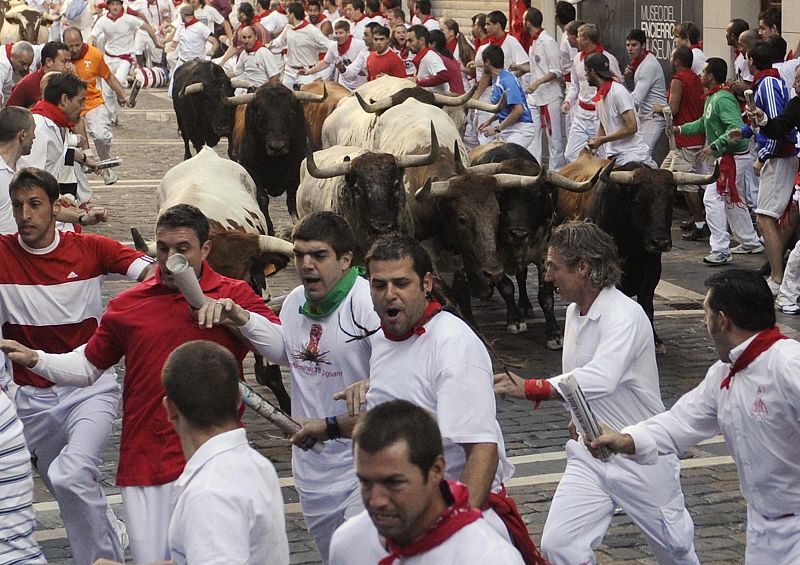 Runners take the Estafeta corner in front of Penajara fighting bulls during the first running of the bulls on the second day of the San Fermin festival in Pamplona
