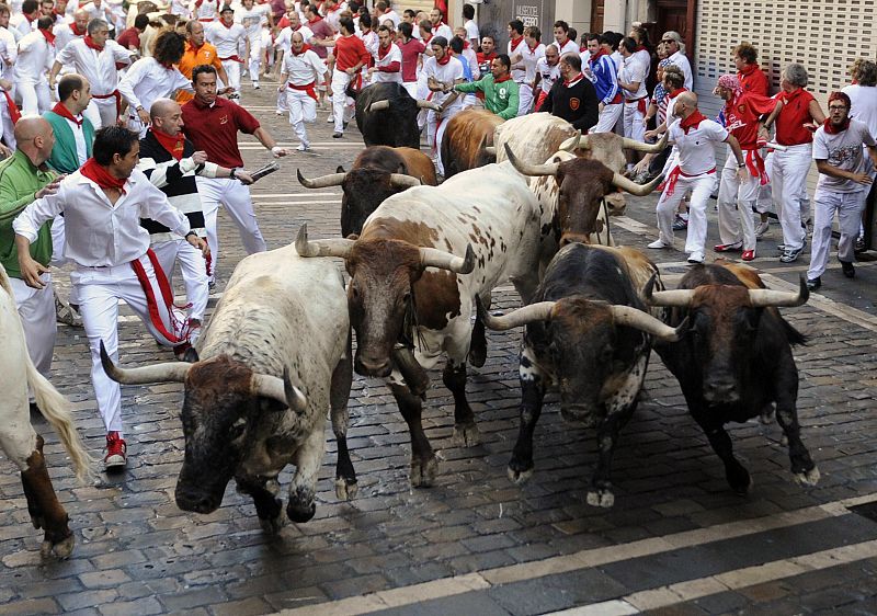 Runners take the Estafeta corner next to Penajara fighting bulls during the first running of the bulls on the second day of the San Fermin festival in Pamplona