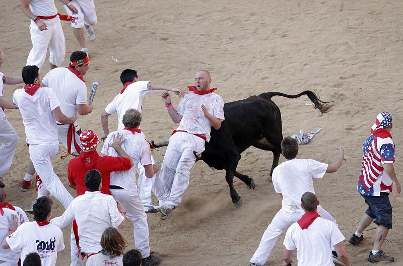 A reveller is tossed by a fighting cow during festivities in the bull ring during the San Fermin festival in Pamplona