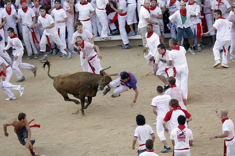 A reveller is tossed by a fighting cow during festivities in the bull ring during the San Fermin festival in Pamplona