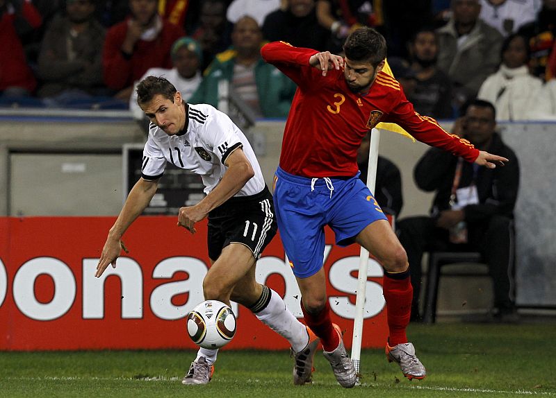 Spain's Pique fights for the ball with Germany's Klose during their 2010 World Cup semi-final soccer match at Moses Mabhida stadium in Durban