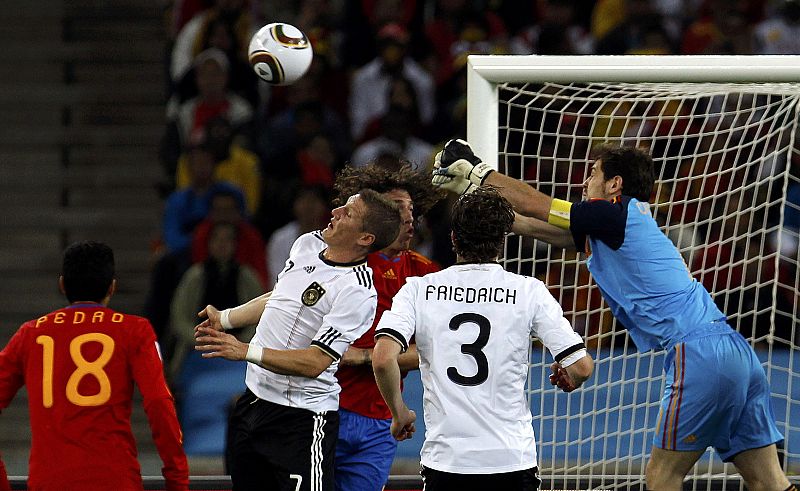 Spain's goalkeeper Casillas punches the ball away from Germany's Schweinsteiger and Friedrich during their 2010 World Cup semi-final soccer match at Moses Mabhida stadium in Durban