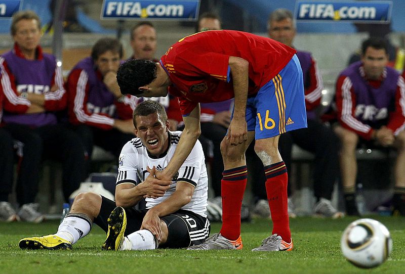 Spain's Busquets lends a hand to Germany's Podolski during their 2010 World Cup semi-final soccer match at Moses Mabhida stadium in Durban