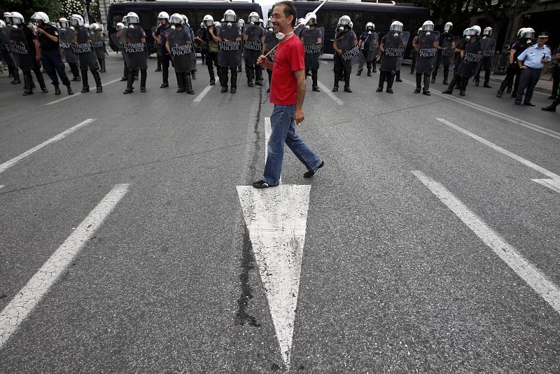 A protester walks in front of a police formation during a rally in Athens