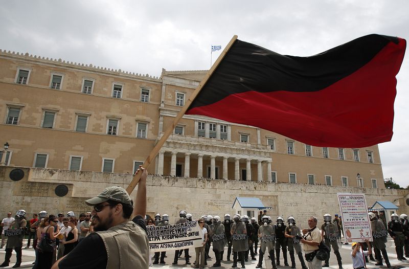 A protester waves a flag in front of the Greek parliament building during a rally in Athens