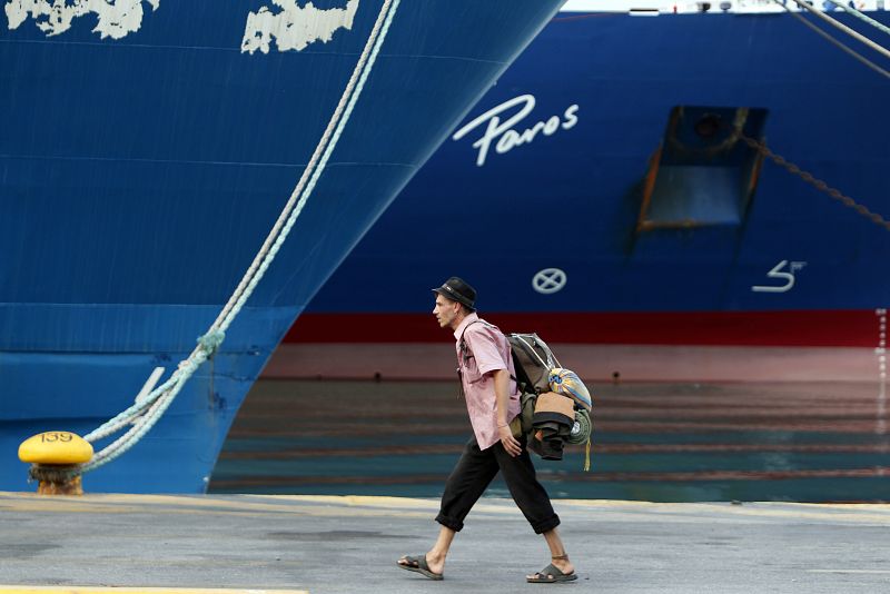 A tourist walks in front of immobilised ferries during a 24-hour strike at the port of Piraeus