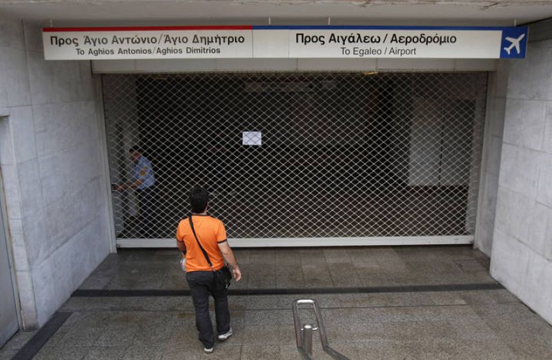 A man walks towards a fence at a closed entrance of a metro station during a 24-hour strike in Athens