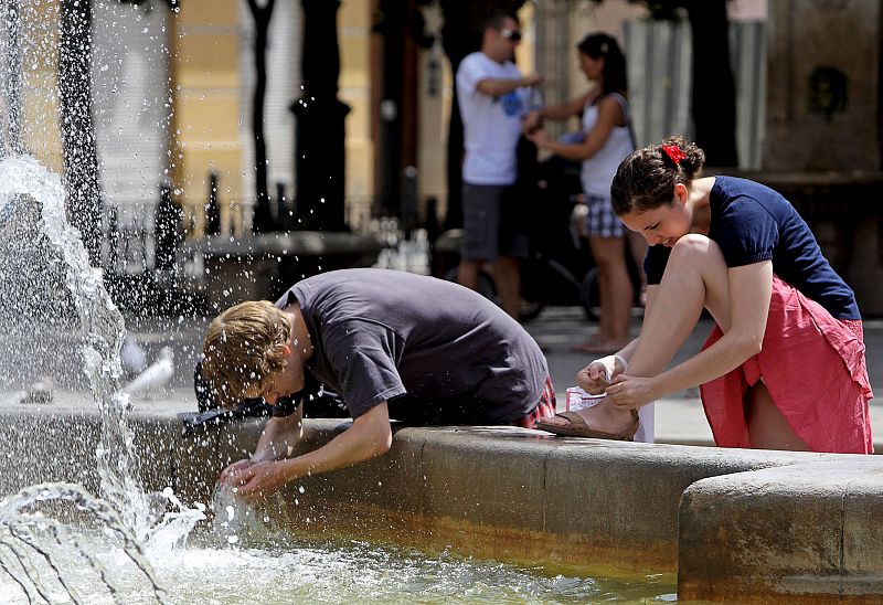 Un joven se refresa en una fuente de la plaza Virgen de Valencia. En esta comunidad se mantiene la alerta amarilla.