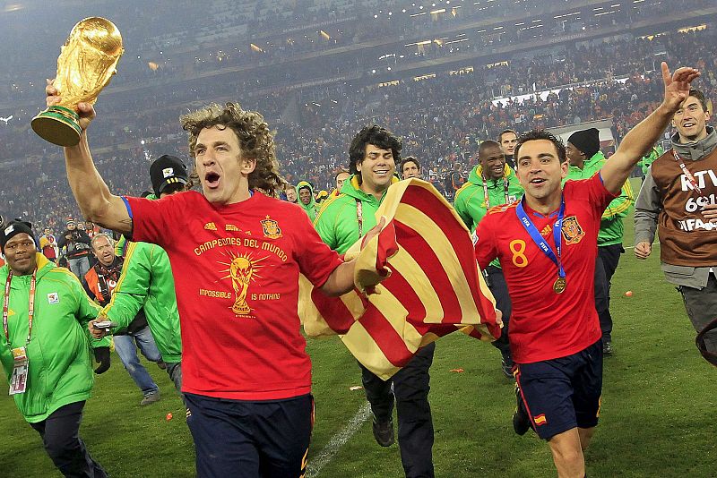 Puyol y Xavi celebran la victoria de España sobre el césped con una 'senyera' catalana.