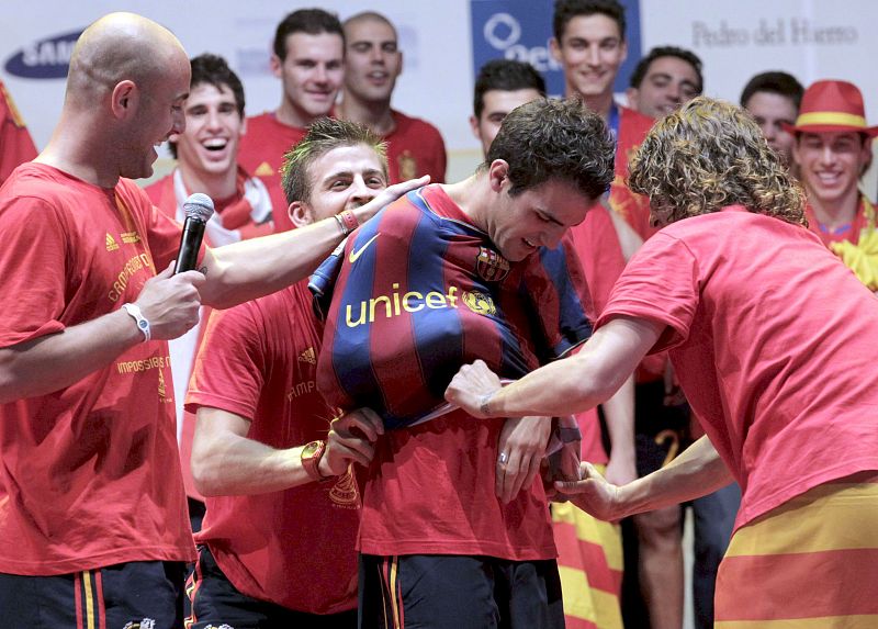 Pique y Puyol ponen una camiseta del FC Barcelona a Cesc Fábregas.