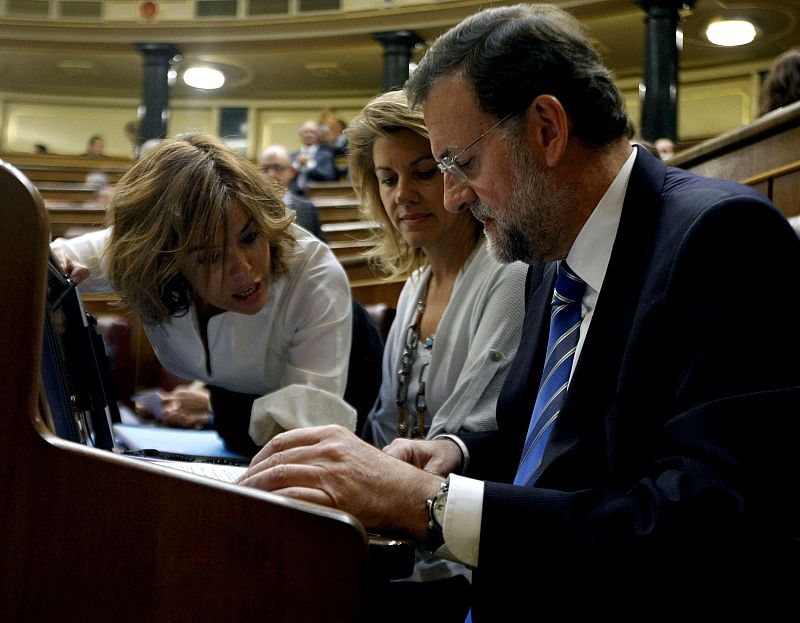 El líder del PP, Mariano Rajoy, la secretaria general nacional del partido, Maria Dolores de Cospedal, y la portavoz popular en el Congreso, Soraya Sáenz de Santamaría, revisan sus notas en el hemiciclo.