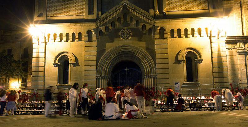 Un grupo de personas se quita sus pañuelos y los deja junto a las velas a la entrada de la Iglesia de San Lorenzo en Pamplona