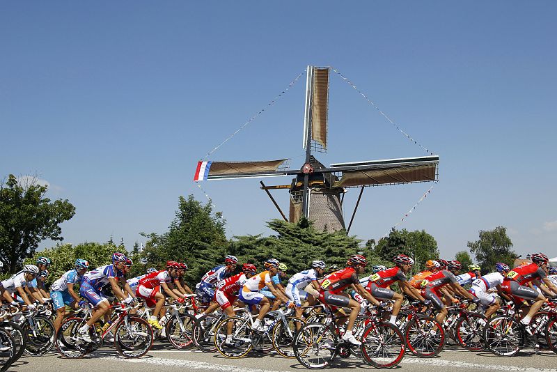 Riders cycle past a windmill during the first stage of the Tour de France cycling race from Rotterdam to Brussels