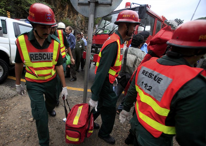 Rescue workers carry a bag containing equipment near the site of the wreckage of a passenger plane which has crashed in the Margalla Hills on the outskirts of Islamabad