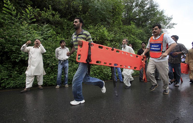 Rescue workers run with a stretcher near the site of the wreckage of a passenger plane which has crashed in the Margalla Hills on the outskirts of Islamabad