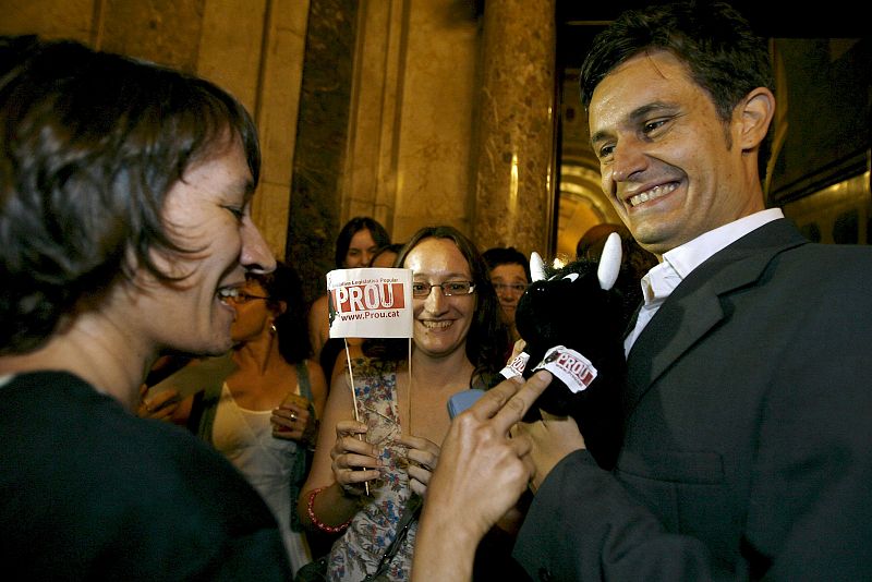 El portavoz de la plataforma Prou!, Leonardo Anselmi, recibe un toro de peluche como regalo de manos de una detractora de las corridas de toros.