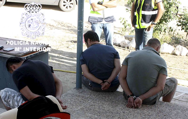 Tres de los detenidos esposados frente a agentes de la policía