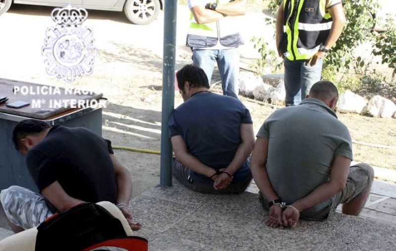 Tres de los detenidos esposados frente a agentes de la policía