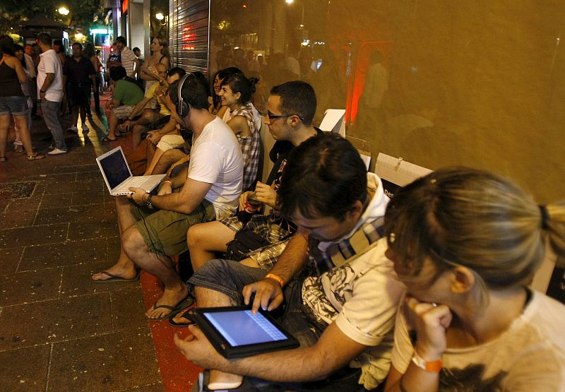 Decenas de personas esperan la apertura de una de las tiendas que han abierto esta medianoche en Madrid para vender las primeras unidades del último móvil inteligente de Apple