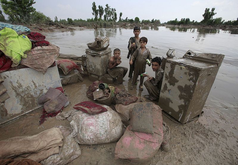 Boy sit with their belonging beside receding flood waters in Nowshera in Pakistan's northwest Khyber-Pakhtunkhwa Province