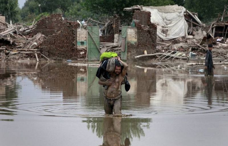 A man carries belonging on his shoulder while wading through receding flood waters in Nowshera, located in Pakistan's northwest Khyber-Pakhtunkhwa Province