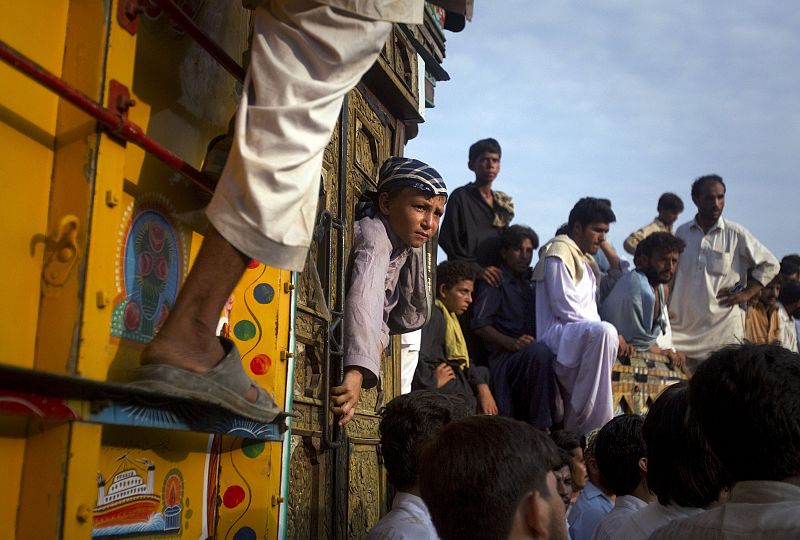 A boy leans out of the window of a cargo truck after townsmen created a blockade, halting traffic until relief supplies were distributed to flood victims in Nowshera Pakistan