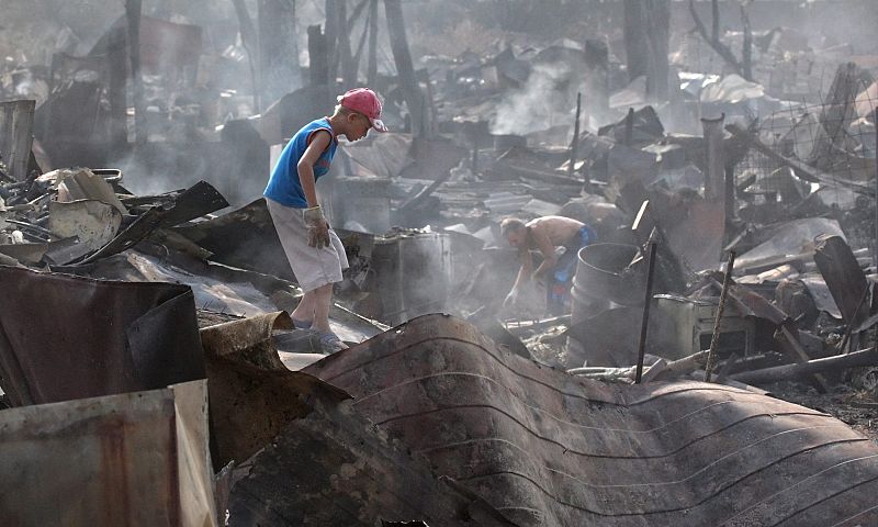 Un niño rebusca entre la basura tras el incendio.