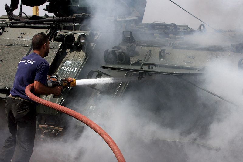 Civiles libaneses apagan el incendio de un vehículo acorazado del ejército libanés