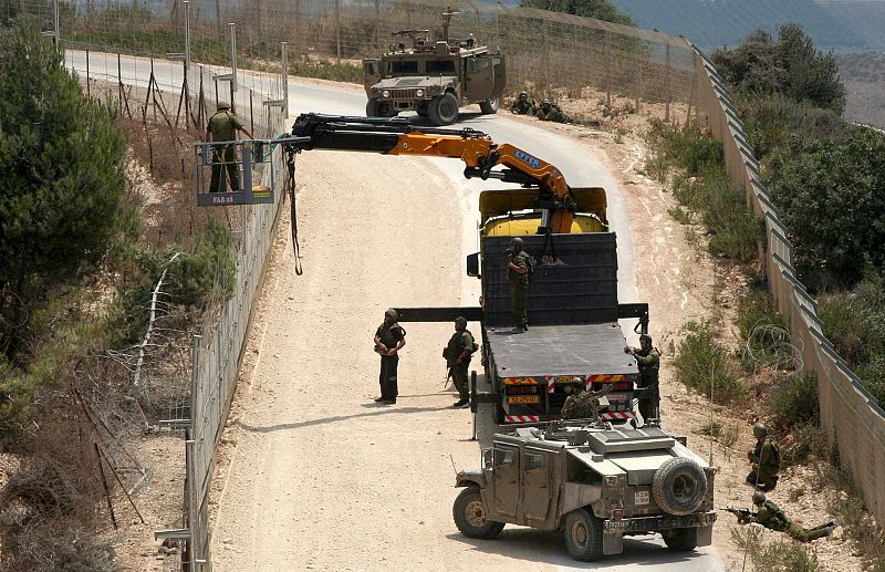 Soldados israelíes utilizan una grúa para cortar un árbol del lado libanés