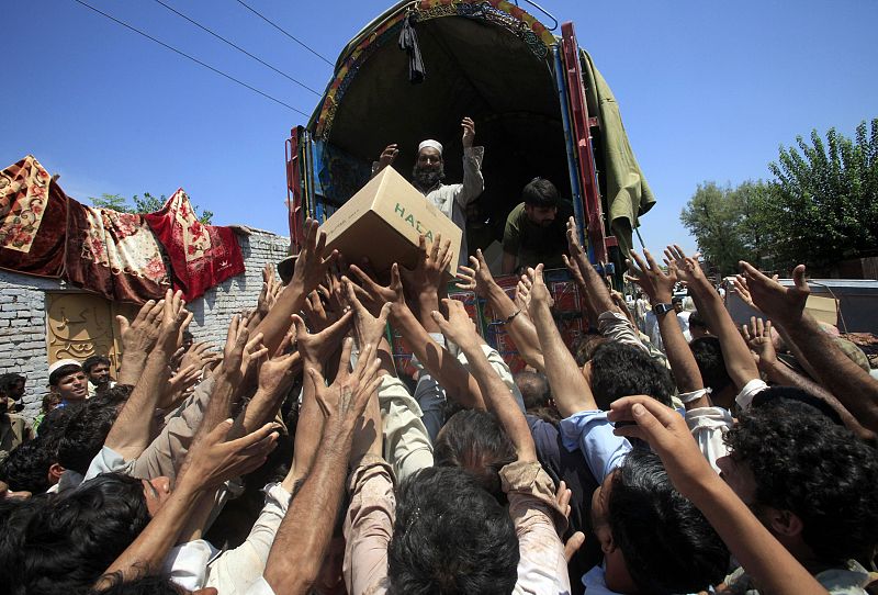 Flood victims raise their hands to collect relief supplies from the Army in Nowshera, located in Pakistan's northwest Khyber-Pakhtunkhwa Province