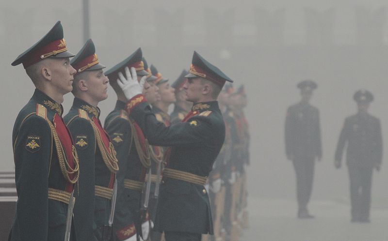 A guard of honour adjusts service caps of his associates as a heavy smog shrouded the capital in Moscow