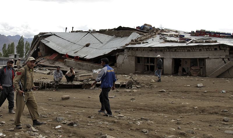 Un policía pasa cerca de las casas que se derrumbaron tras las inundaciones repentinas en Leh