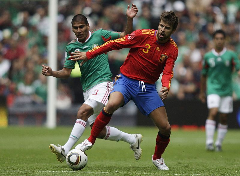 Piqué y Salcido pelean por un balón.