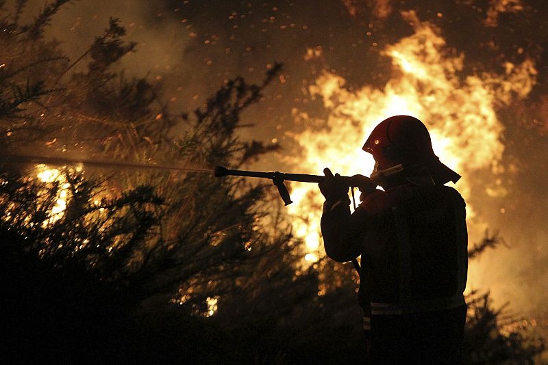 Un miembro de una brigada lucha contra el incencio en Fornelos de Montes