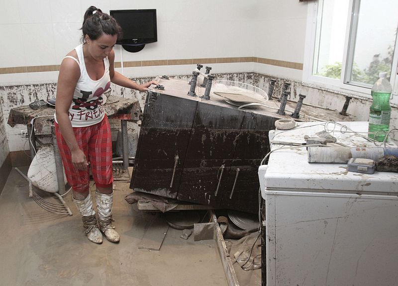 Una mujer observa el estado en el que han quedado los muebles de su vivienda en la localidad de Aguilar de la Frontera.