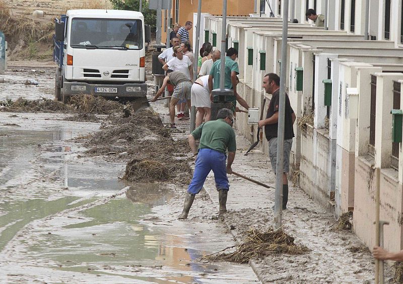 Unos vecinos de Aguilar de la Frontera limpian sus casas después de las fuertes lluvias.