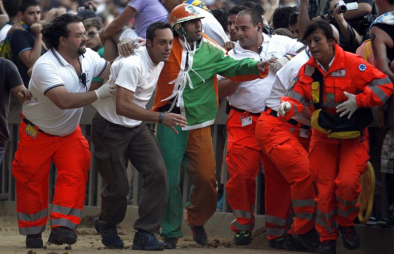 Jockey of Selva parish Alberto Ricceri is helped after falling off his horse during the Palio race in Siena