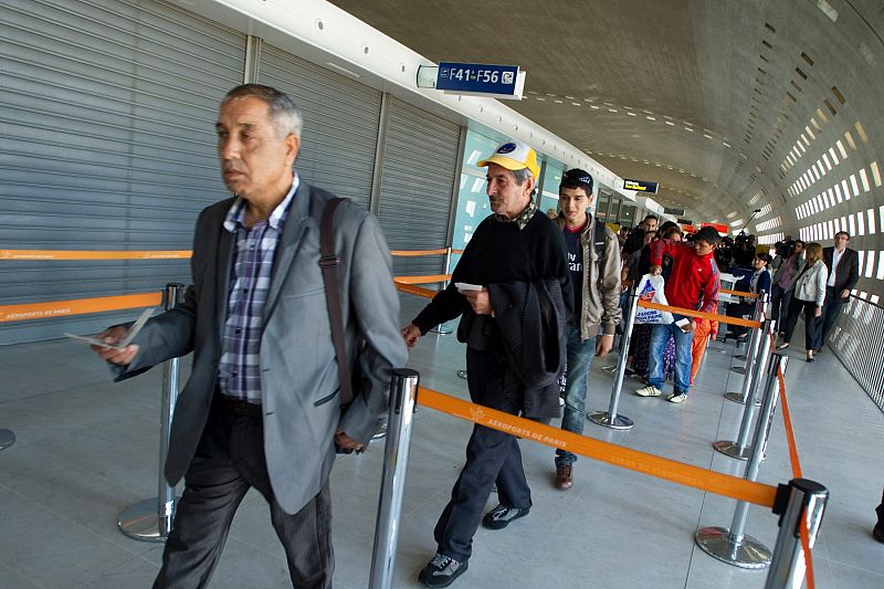 Roma who are part of a voluntary repatriation scheme hold travel documents at Roissy Charles-de-Gaulle airport