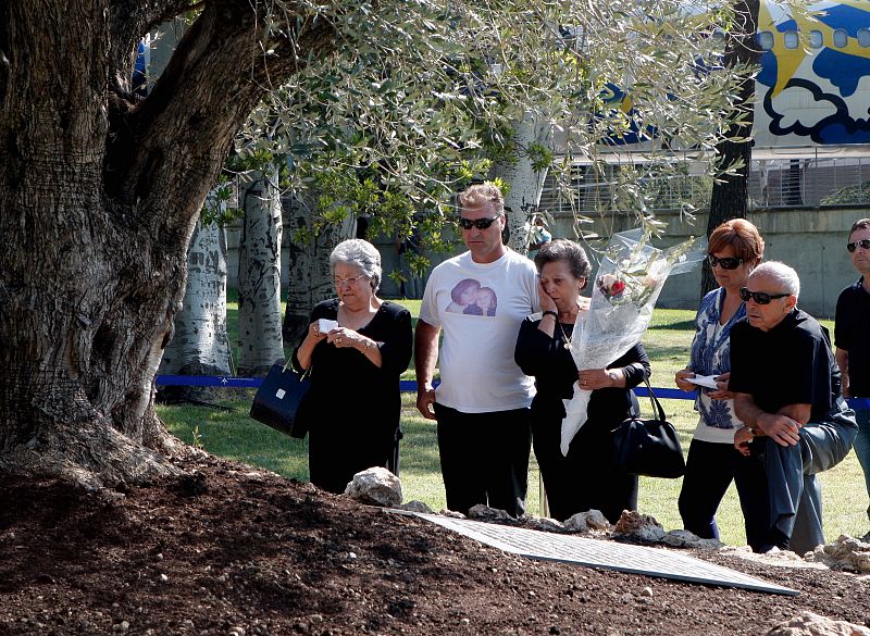 Algunos familiares lloran junto al olivo situado en el jardín de la Terminal 2 del aeropuerto, al recordar a sus familiares en el acto de homenaje.